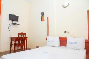 a bedroom with a bed with white sheets and a desk at Hotel Résidence Les Racines in Pira