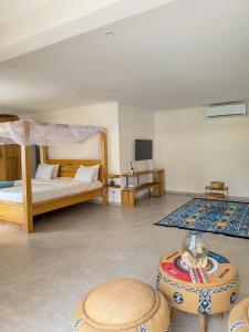 a bedroom with a bed and a table in a room at Au Paradis de Jeanne in Ngaparou +70 photos