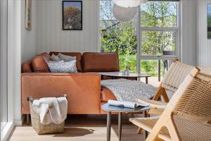 a living room with a leather couch and two chairs at 0370-Romo-Vestergardsvaenget-13 in Høm