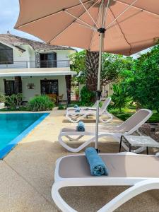a group of lounge chairs and an umbrella next to a pool at Au Paradis de Jeanne in Ngaparou