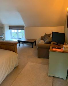 a living room with a couch and a desk with a computer at Corner Lodge in North Tawton