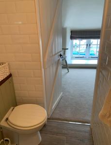 a bathroom with a toilet and a hallway at Corner Lodge in North Tawton