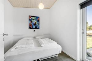 a white bedroom with a bed and a painting on the wall at 0323-Romo-Vestergade-359 in Høm