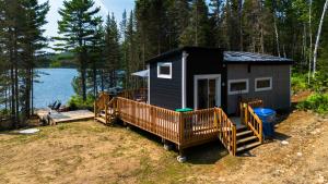 a black tiny house in the woods next to a lake at Espace des Grands-Ducs - Domaine de Lacs et de forêt in Sacré-Coeur-Saguenay
