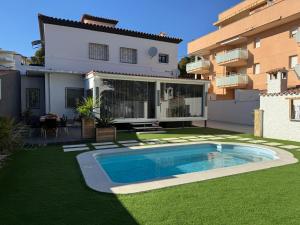 a yard with a swimming pool in front of a house at Evian Cala in Miami Platja