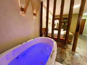 a bathroom with a blue tub and a bed at Pousada Noah Noah Milagres in São Miguel dos Milagres