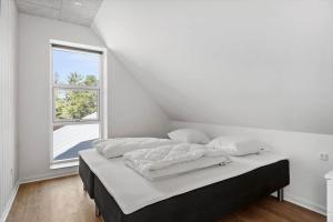 a bedroom with a bed with white sheets and a window at 2007-Romo-Juvrevej-43 in Høm