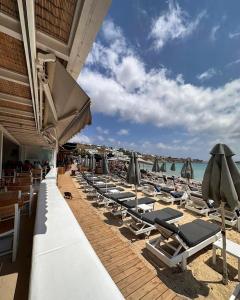 a row of lounge chairs and umbrellas on a beach at Acrogiali Beachfront Hotel Mykonos in Platis Gialos