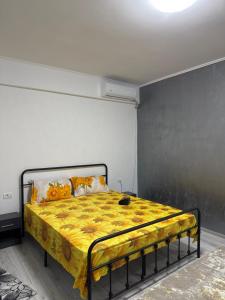 a bedroom with a bed with a yellow blanket on it at Garsonieră in Tulcea