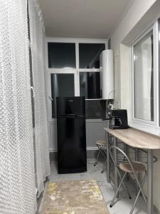 a kitchen with a black refrigerator and a table at Garsonieră in Tulcea