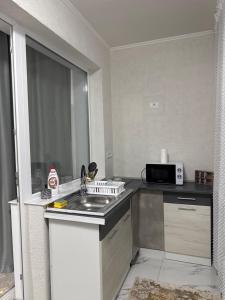 a small kitchen with a sink and a microwave at Garsonieră in Tulcea