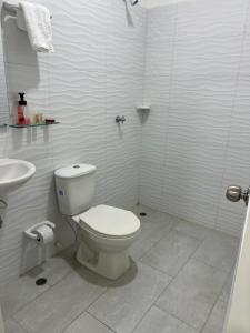 a white bathroom with a toilet and a sink at Aparta hotel brisas Del tayrona in Santa Marta