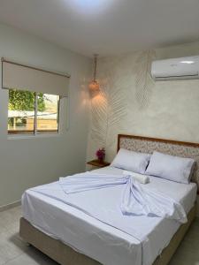a bedroom with a large bed with white sheets and a window at Aparta hotel brisas Del tayrona in Santa Marta