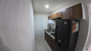 a kitchen with a black refrigerator and wooden cabinets at Departamento Belinda in Ixtapa