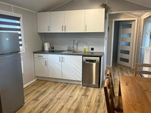 a kitchen with white cabinets and a wooden floor at Domki na Mazurach "Malinka" in Suchy Róg