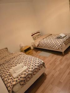 two beds in a room with wooden floors at Séjour Eau Vive Proche commerces et Metro in Créteil