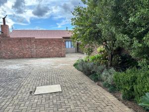 a brick driveway with a brick wall and a building at Spring Day in Piet Retief