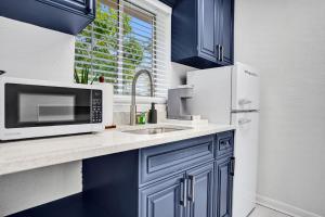 a kitchen with blue cabinets and a microwave and a sink at Lucerne Collection Private 4-Unit Building in Lake Worth