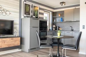 a kitchen with a table and chairs and a tv at Apartment Deichblick in Büsum