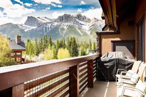 a balcony with chairs and a view of mountains at Tranquility at Rundle Cliffs Lodge in Canmore
