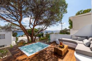 a patio with a pool and a couch and a tree at Sunset Cove in Agios Ioannis Mykonos