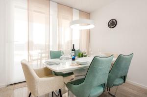 a dining room with a white table and green chairs at Villa Mare e Monti in Nin