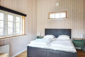 a large bed in a room with two windows at 12228-Sjaellands-Odde-Strandvaenget-23 in Yderby