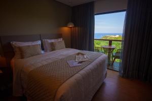 ein Hotelzimmer mit einem Bett und einem großen Fenster in der Unterkunft Miragem Noronha in Fernando de Noronha + 48 Fotos