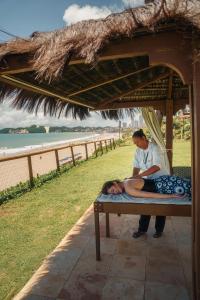 a man sitting on a bed next to the beach at El Aram Natal Mar in Natal