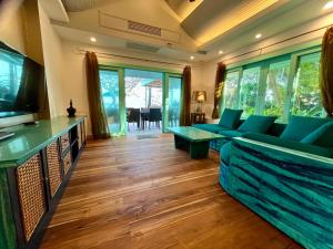a living room with blue couches and a television at Villa Sunrise - Golden Beachfront in Nathon Bay