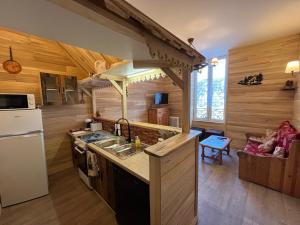 a kitchen in a log cabin with a sink and a refrigerator at Les Roitelets "MONTAGNARD" - Appartement T2 avec Mezzanine - Thème Montagne - Entièrement NEUF - Classé 3 étoiles - Proche Centre-ville & Thermes - Ménage et Linge de maison INCLUS in La Bourboule