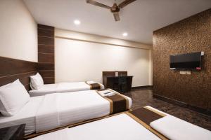 a hotel room with two beds and a flat screen tv at Hotel Well Suites Koramangala in Bangalore +35 photos