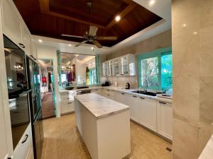 a kitchen with white cabinets and a ceiling fan at Villa Sunrise - Golden Beachfront in Nathon Bay