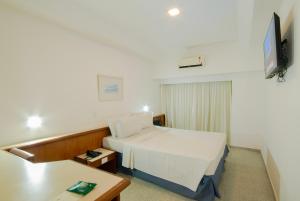 a hotel room with a bed and a tv at Hotel Bandeirantes in Rio de Janeiro