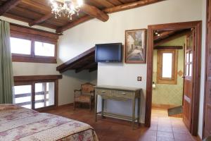 Un dormitorio con una cama y un televisor en la pared. en Posada La Gatera, en Pedro Bernardo