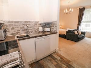 a kitchen with a sink and a living room with a bed at Arkwright in Matlock