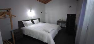 a bedroom with a large white bed with white sheets at Casas do Lourenço in São Roque do Pico