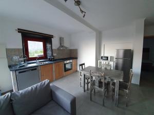 a living room with a table and a kitchen with a couch at Casas do Lourenço in São Roque do Pico