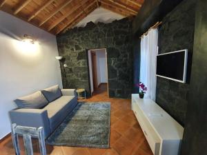 a living room with a couch and a tv at Casas do Lourenço in São Roque do Pico