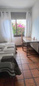 a bedroom with a bed and a table and a window at 203 Barra Refúgio in Tramandaí