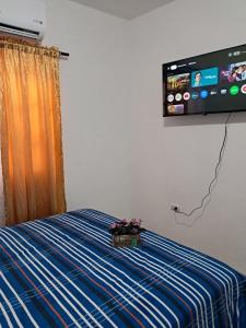a bedroom with a bed with a tv on the wall at Mario Aparta Estudio in San Felipe de Puerto Plata