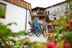 two men standing with bikes in front of a building at Hotel Alpina nature-wellness in Wenns