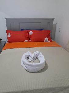 a white towel on a bed with red pillows at Mario Aparta Estudio in San Felipe de Puerto Plata