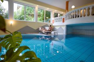 a man and a woman sitting in chairs in a swimming pool at Hotel Alpina nature-wellness in Wenns