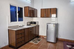 a kitchen with wooden cabinets and a stainless steel refrigerator at Furnished Studio - Cite Progres in Djibouti