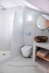 a white bathroom with a toilet and a sink at Mylos Design Suites in Perissa
