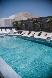 a swimming pool with lounge chairs and a swimming pool at Mylos Design Suites in Perissa