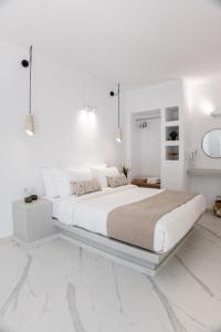 a white bedroom with a large bed and a mirror at Mylos Design Suites in Perissa