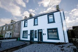 a white house with blue doors and windows at Penthouse at the White House near Edinburgh in Bathgate