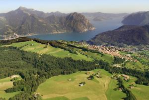 an aerial view of a golf course with a lake and mountains at Casa Gioia Alpina Mountain Lake Iseo Hospitality in Bossico